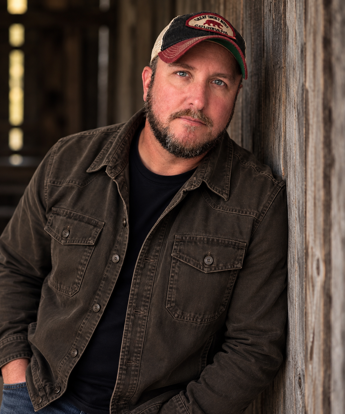 Ron Day leaning against a weathered wooden wall